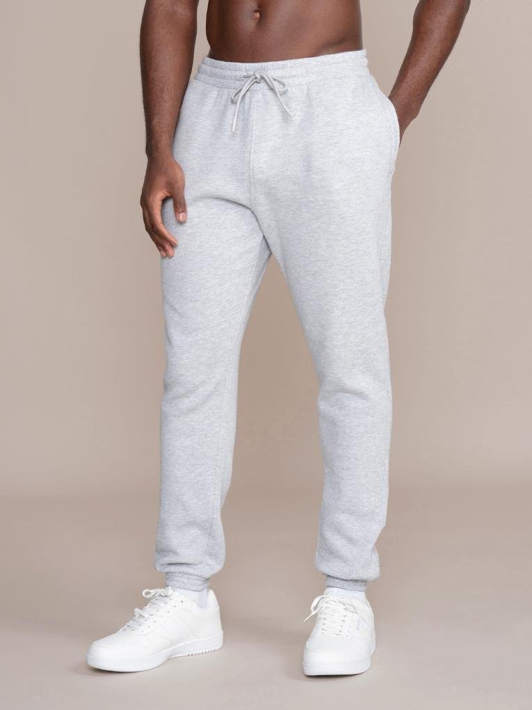 Man modeling slim fit light gray jogger sweatpants with drawstring and white sneakers.